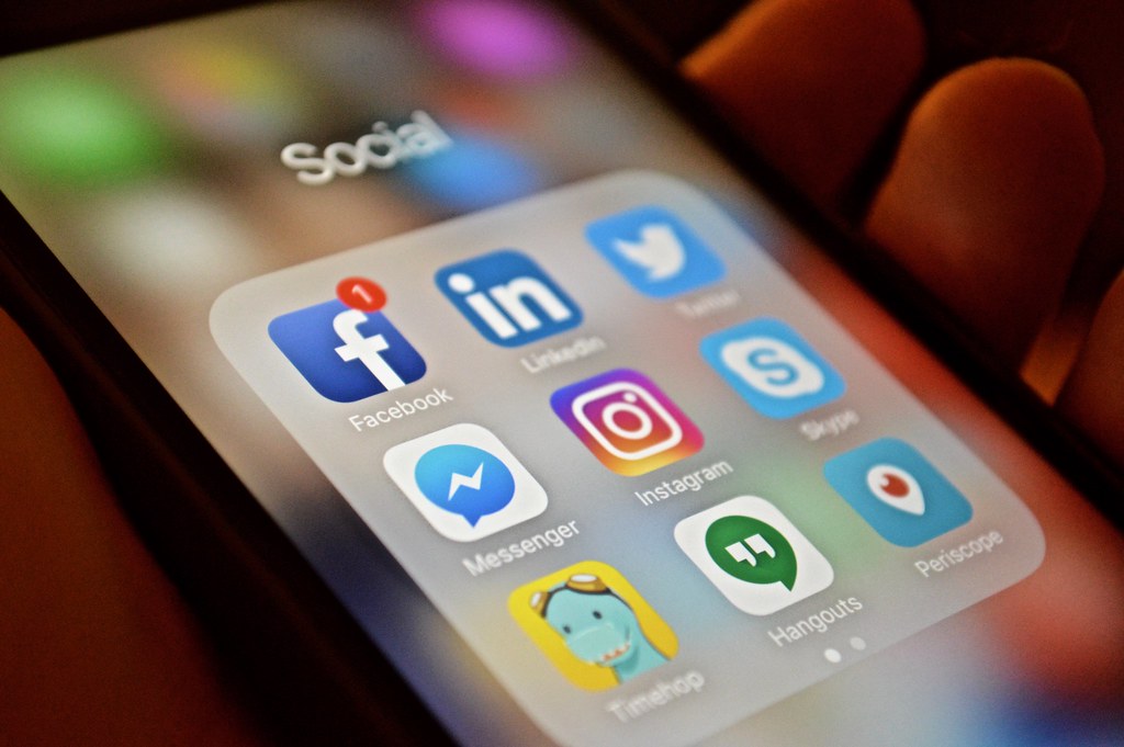 an iphone showing the app icons to various social media platforms. notably linkedin, facebook, twitter, skype, instagram, hangours, and messenger