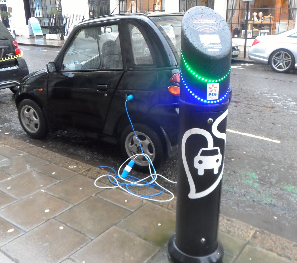 an electric vehicle charging point on the street charging a car. and I am sorry, EDF Energy, this charging point looks like a painted abomination with christmas lights on it