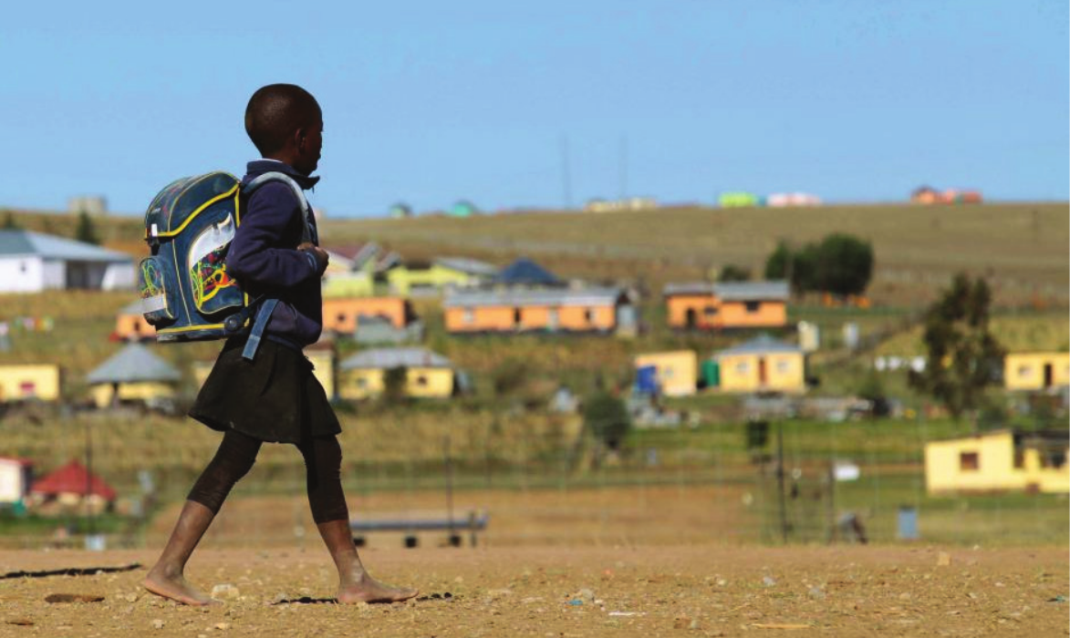 A girl is walking to school through a village in Africa