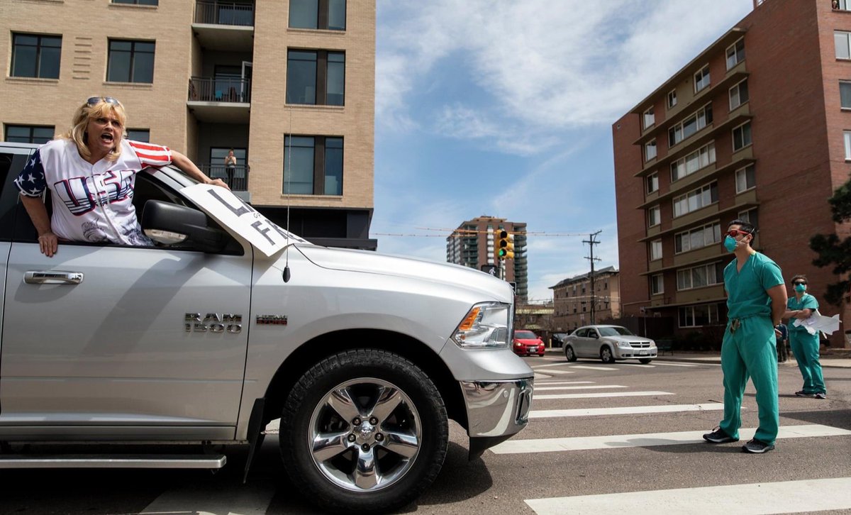 a screaming protestor in a large car in front of a nurse